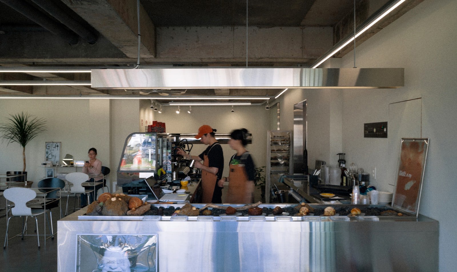 Two baristas in aprons preparing drinks behind a modern café counter